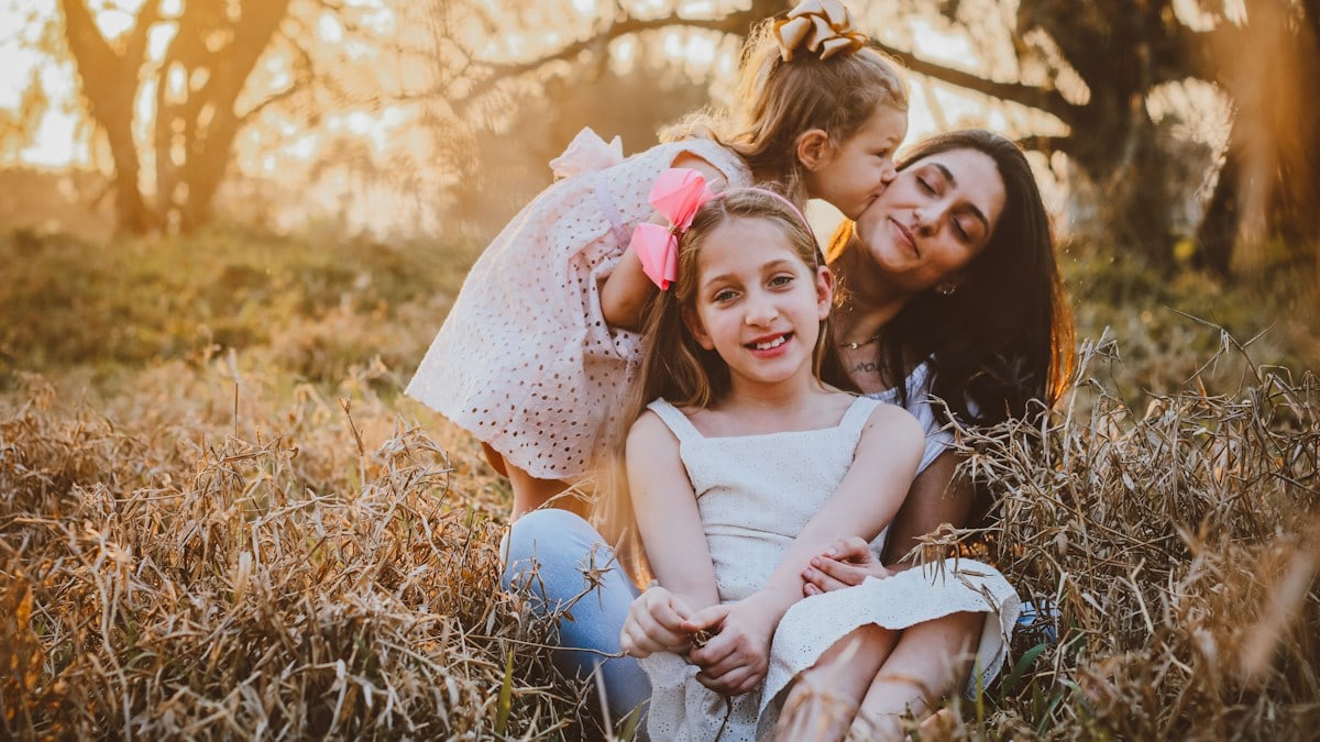 a family of three sitting in a field of tall grass
